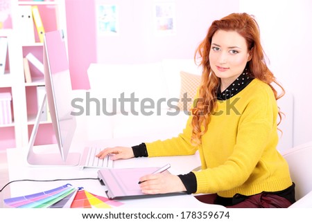 Young woman graphic designer working using pen tablet in workplace
