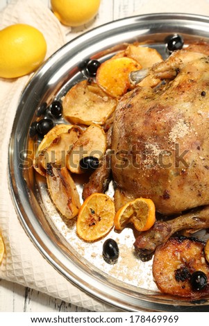 Whole roasted chicken with vegetables on tray, on wooden background