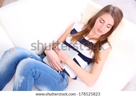 Young woman resting with tablet on sofa at home