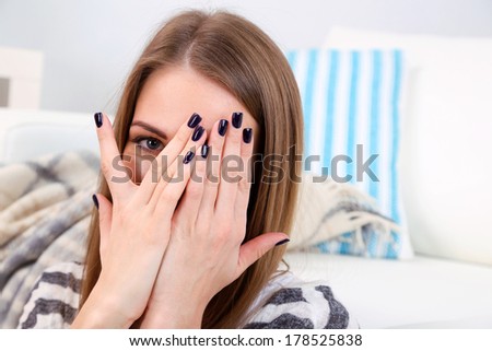 Young woman  watching scary movie, at home, close-up