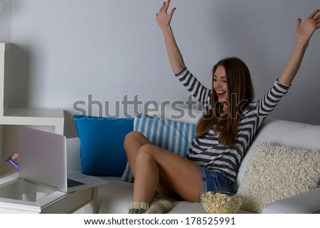 Young woman resting on  sofa and watching scary movie, at home