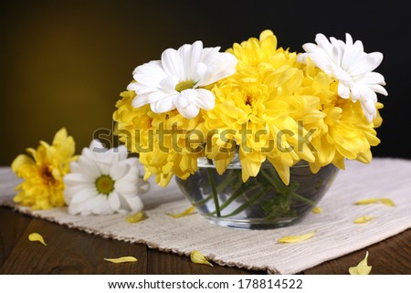 Beautiful chrysanthemum flowers in vase on table on dark yellow background