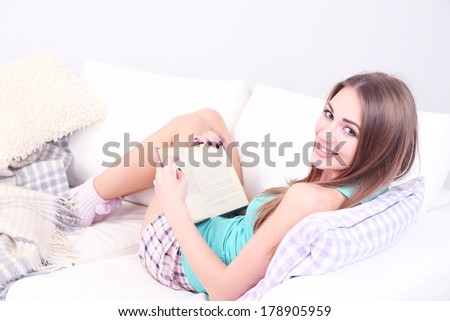 Young woman resting with book on sofa at home