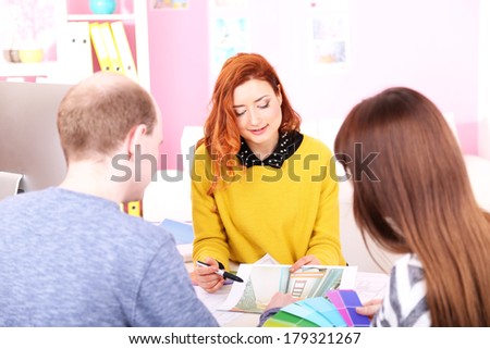 Young woman designer with clients in office