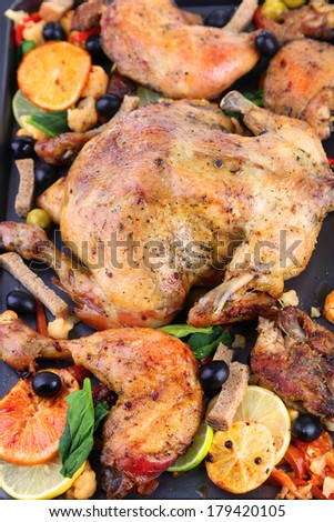 Whole roasted chicken with vegetables on tray, close-up