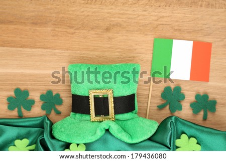 Saint Patrick day hat with clover leaves and Irish flag on wooden background