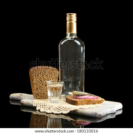 Bottle of vodka, sandwich with salted fish and glasses on wooden board, isolated on black