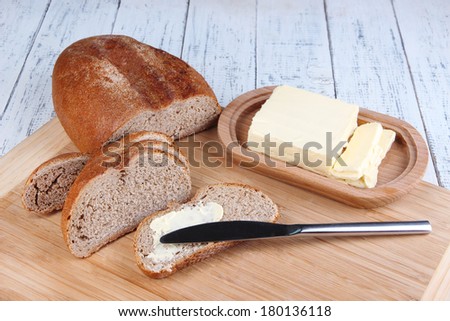 Rye bread with butter on cutting board on wooden background