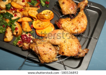 Homemade fried chicken drumsticks with vegetables on pan, on wooden background