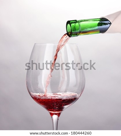 Pouring wine into wineglass isolated on white