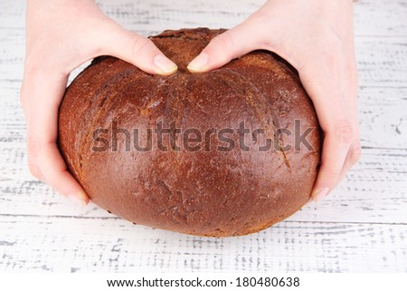 Hands breaking bread on wooden background