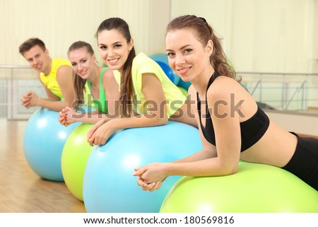 Group of young people training with gymnastic ball in gym