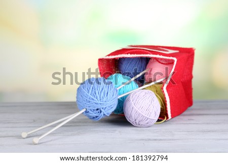 Woolen balls of yarn in rustic craft bag, om wooden table, on light background