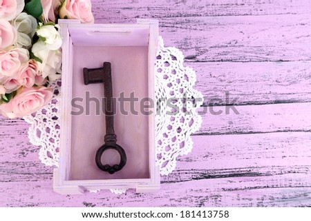 Key to success and happiness. Composition with key in wooden box and flowers. Conceptual photo. On color wooden table, on light background