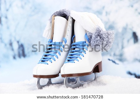 Figure skates and hat on winter background