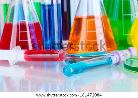 Different laboratory glassware with color liquid on blue background