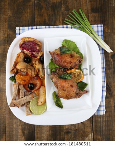 Homemade fried chicken drumsticks with vegetables on plate, on wooden background
