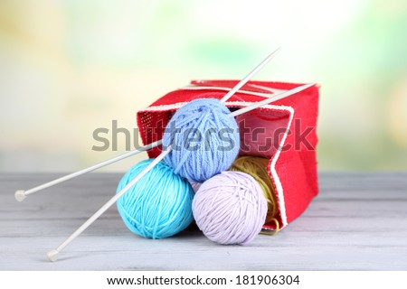 Woolen balls of yarn in rustic craft bag, om wooden table, on light background
