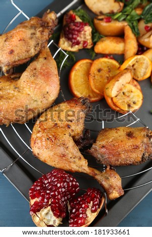 Homemade fried chicken drumsticks with vegetables on pan, on wooden background