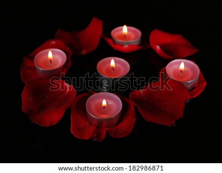 Beautiful rose petals with candle, on dark background