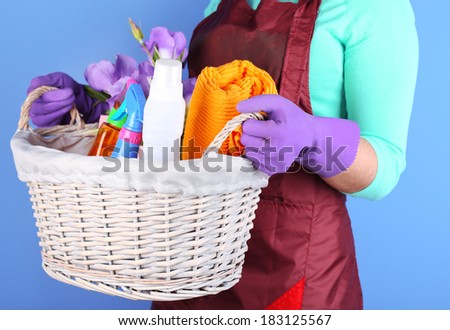Housewife holding basket with cleaning equipment on color background. Conceptual photo of spring cleaning.