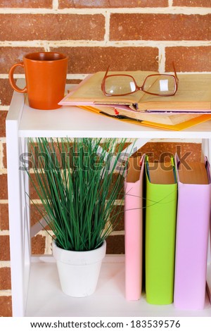 Composition with glasses and books, on cabinet, on color wall background