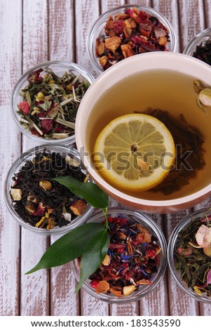 Cup of tea with aromatic dry tea in bowls on wooden background