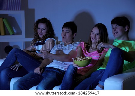Group of young friends watching television at home of blacking-out