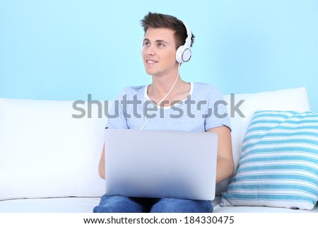 Guy sitting on sofa and  listening to music on blue background