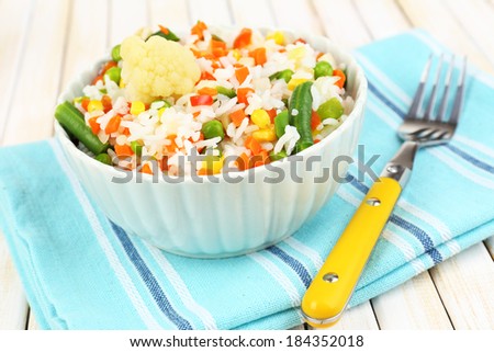 Cooked rice with vegetables on wooden table close up
