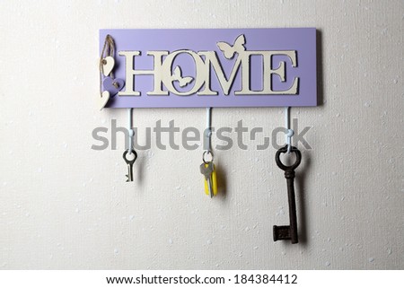 Keys hanging from hooks, on light wall background