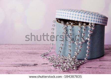 Decorative box with beads on table on bright background
