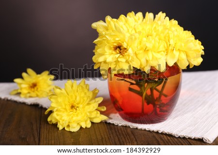 Beautiful chrysanthemum flowers in vase on table on dark  background