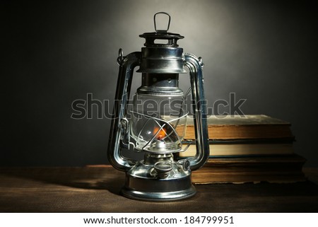 Kerosene lamp and books on dark grey background