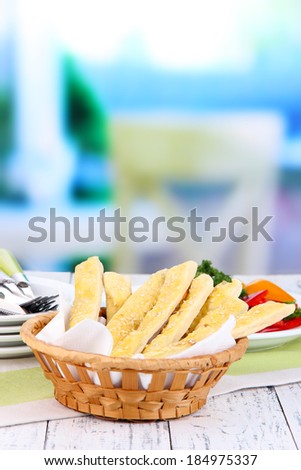 Bread sticks  in wicker basket on wooden table on light background