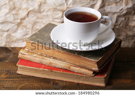 Cup of hot tea on books on table on paper background