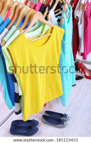 Different clothes on hangers and shoes on light background