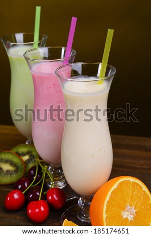 Milk shakes with fruits on table on dark yellow background