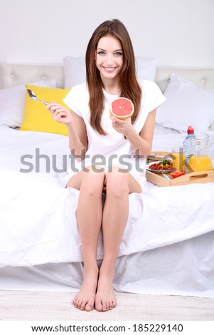 Young beautiful woman on bed with light breakfast