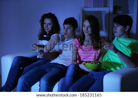Group of young friends watching television at home of blacking-out