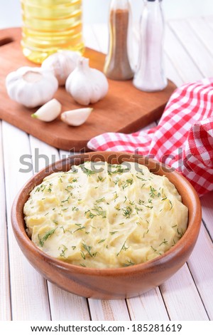 Delicious mashed potatoes with greens in bowl on table close-up