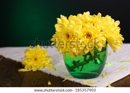 Beautiful chrysanthemum flowers in vase on table on dark green background