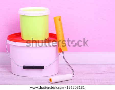 Paints and roll on floor in room on wall background