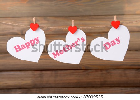 Happy Mothers Day message written on paper hearts on brown background