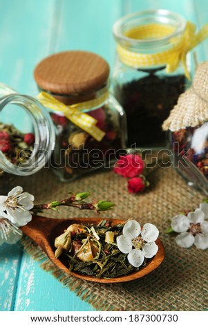 Assortment of herbs and tea in glass jars on wooden background