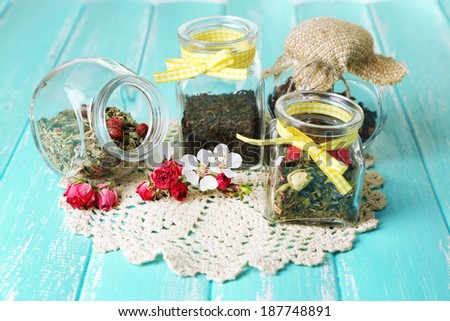 Assortment of herbs and tea in glass jars on wooden table background