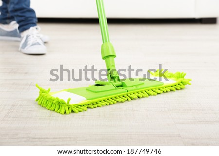 Woman with mop cleaning wooden floor from dust