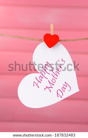 Happy Mothers Day message written on paper heart on pink background
