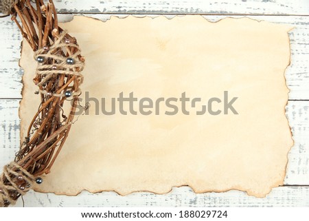 Old paper sheet and beautiful rustic wreath, on wooden background