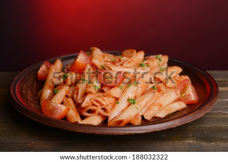 Pasta with tomato sauce on plate on table on red background